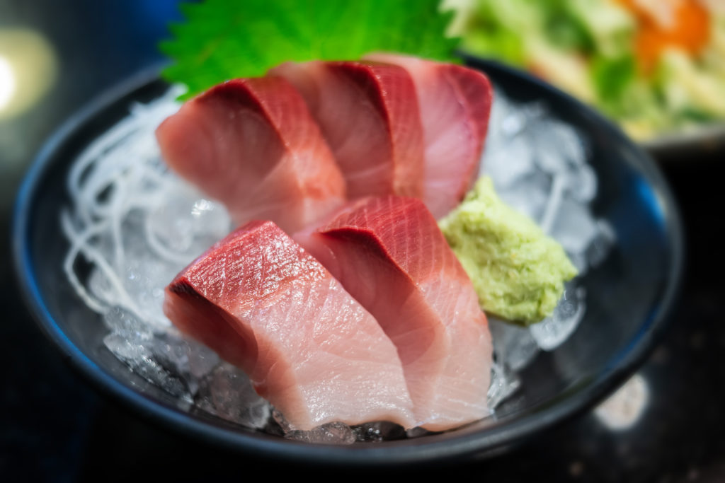 Raw Yellow tail fish or Hamachi sashimi in Japanese food name photo with very low lighting and wide aperture.